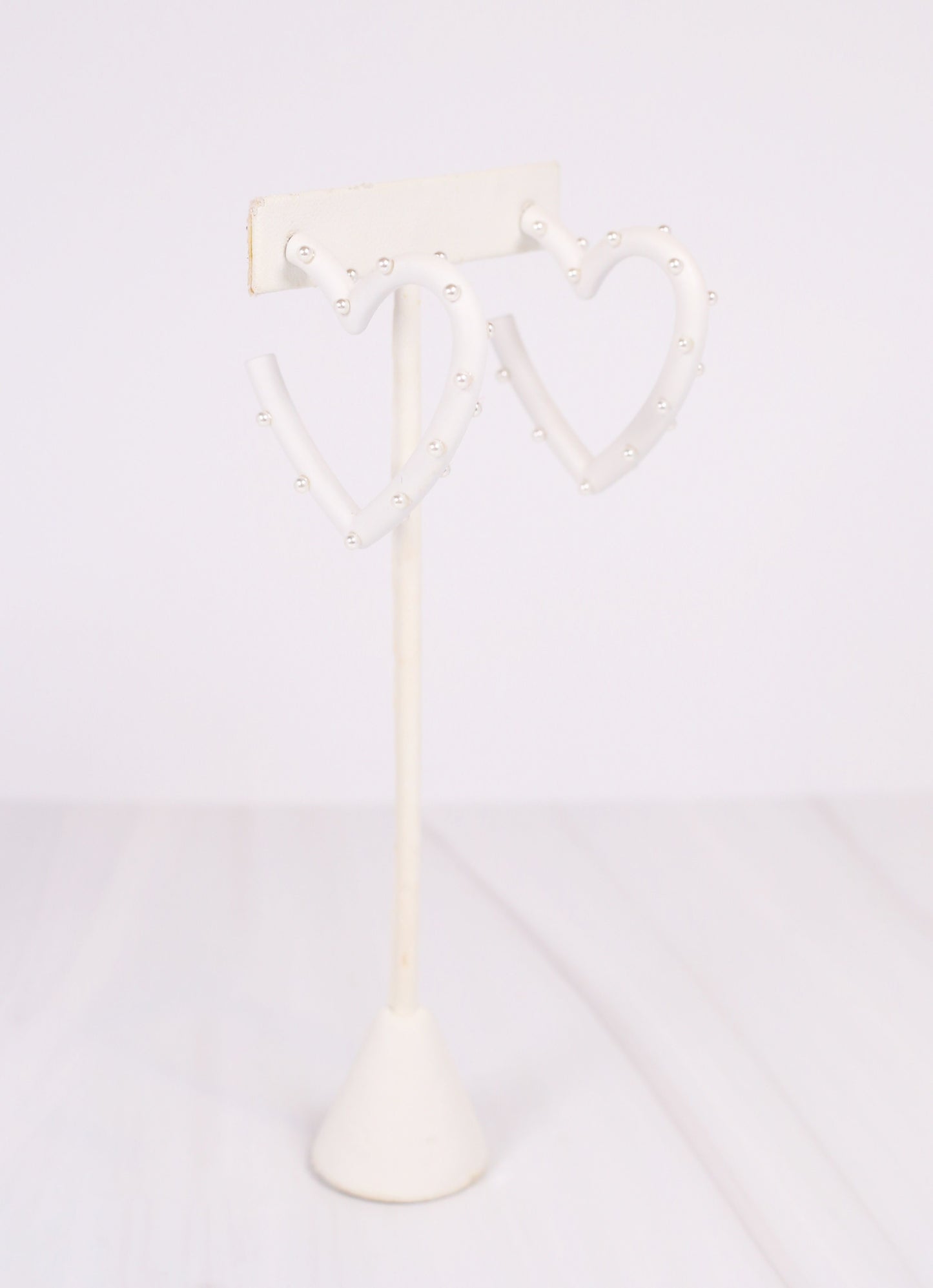 This coated metal heart earring is adorable! It is studded with pearl accents on a post back. Dimensions: 2" diameter